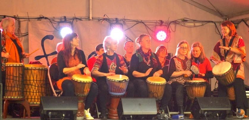 The Drum Connection group performing on stage under coloured lights